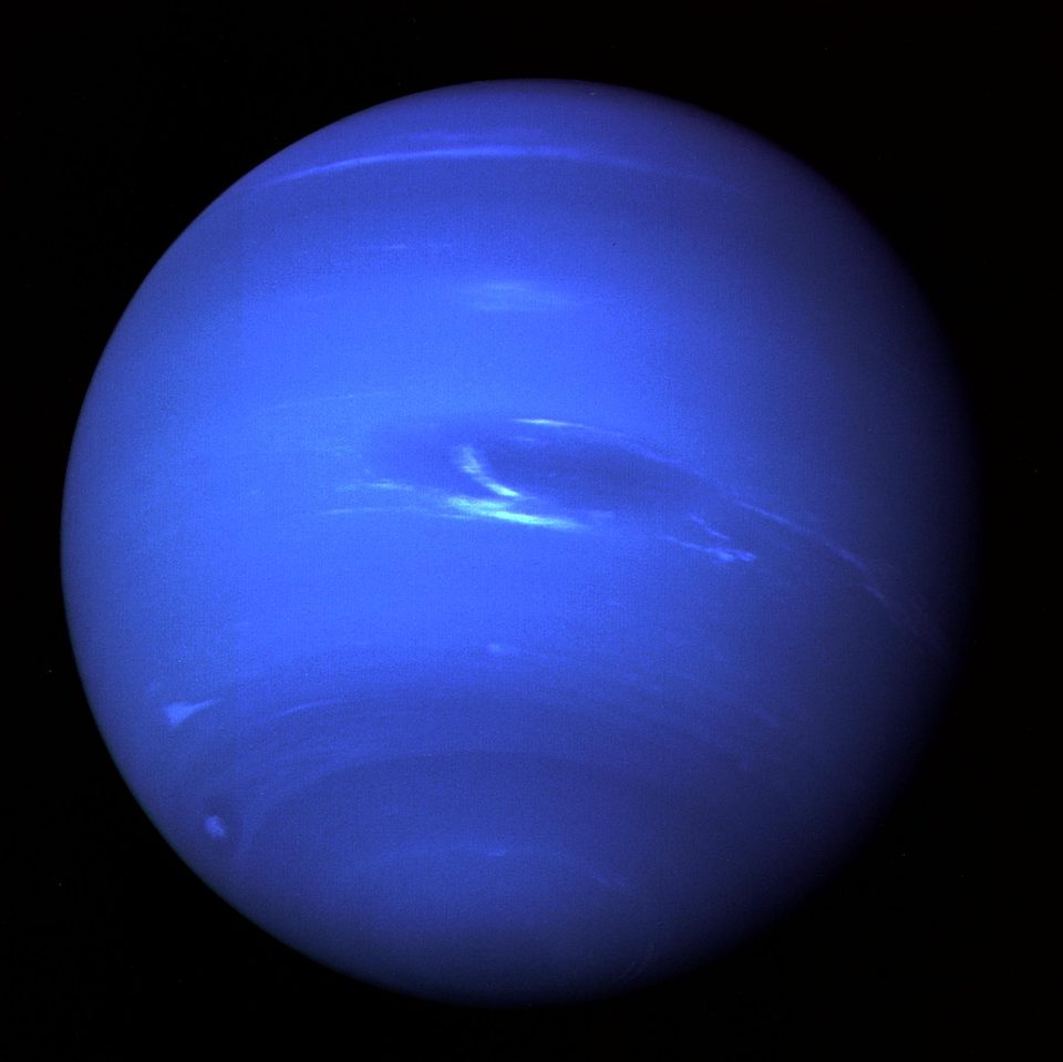 Neptune photographed by Voyager 2, a deep blue globe with white cloud streaks and the dark oval of the Great Dark Spot.
