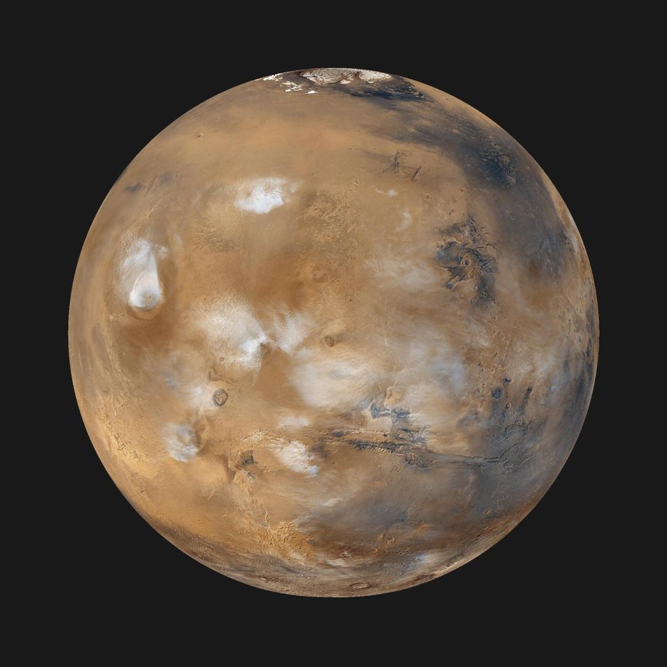 Mars photographed from orbit, a rust coloured globe with a bright white polar cap and dark markings across its surface.